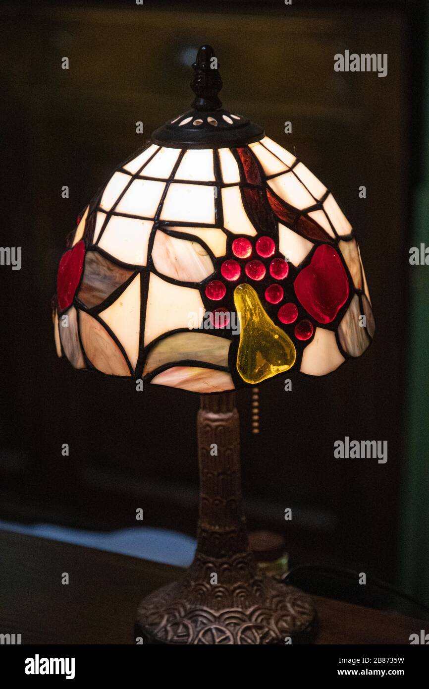 Nahaufnahme der antiken Tischleuchte mit Lampenschirm aus Buntglas auf schwarzem Hintergrund. Glühende Mosaiklampe in Form einer Kuppel. Vintage-Tischleuchte mit verzierten l Stockfoto