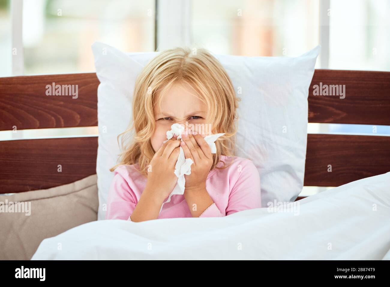 Porträt eines kranken kleinen Mädchens mit runniger Nase, das an Kälte oder Grippe leidet, während es zuhause im Bett liegt. Viruserkrankung. Coronavirus Konzept. Konzept für das Gesundheitswesen Stockfoto