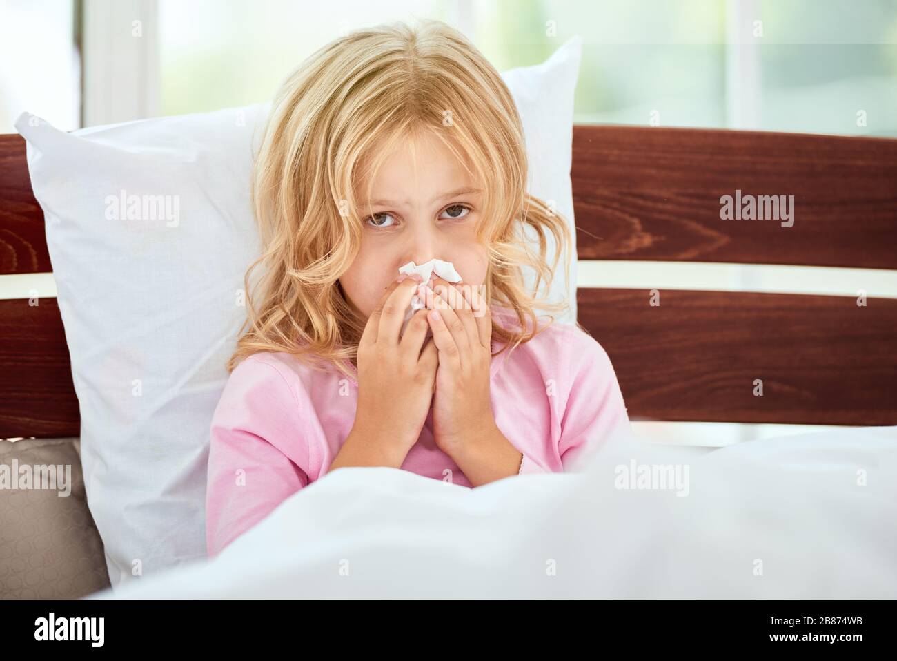 Portrait des kleinen Mädchens mit runniger Nase, das an Kälte oder Grippe leidet, während es zu Hause im Bett liegt. Viruserkrankung. Coronavirus Konzept. Konzept für das Gesundheitswesen Stockfoto