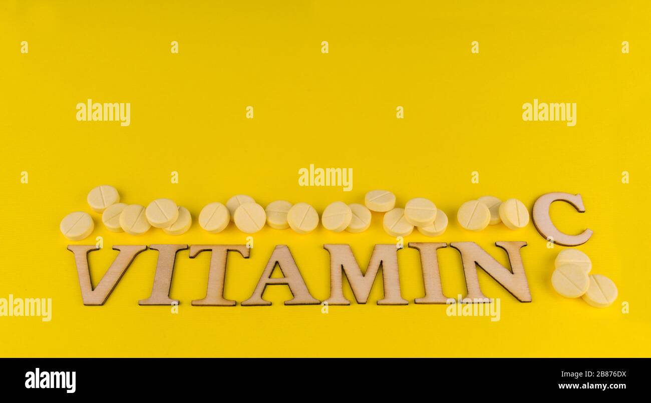Die Aufschrift von Vitamin C und vielen Tabletten auf gelbem Hintergrund. Kopierbereich. Stockfoto