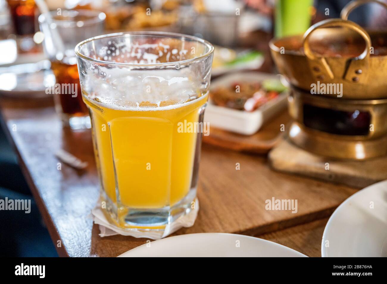 Trinken von Handwerker-Bier mit Schaum aus großem Glas auf Holztisch im Restaurant Stockfoto