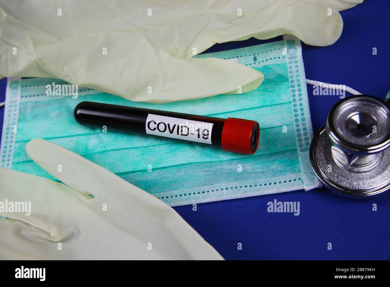 Selbstschutz- und Testgerätekonzept in der Koronakrise: Isolierte Operationsschutzmaske und Gummihandschuhe mit handgeschriebenem Wort Covid-19 Stockfoto