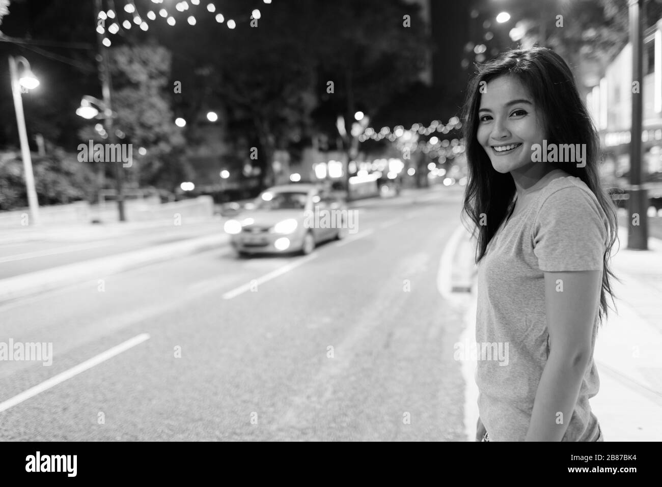 Junge schöne asiatische Frau, die nachts in den Straßen der Stadt umherstreift Stockfoto