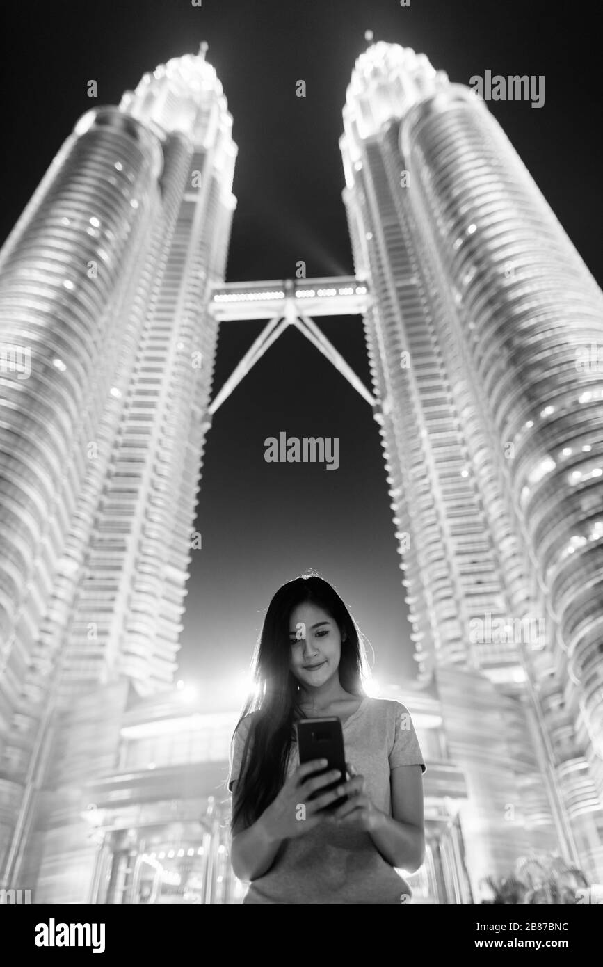 Junge, schöne asiatische Frau mit Blick auf die Zwillingstürme in der Nacht Stockfoto