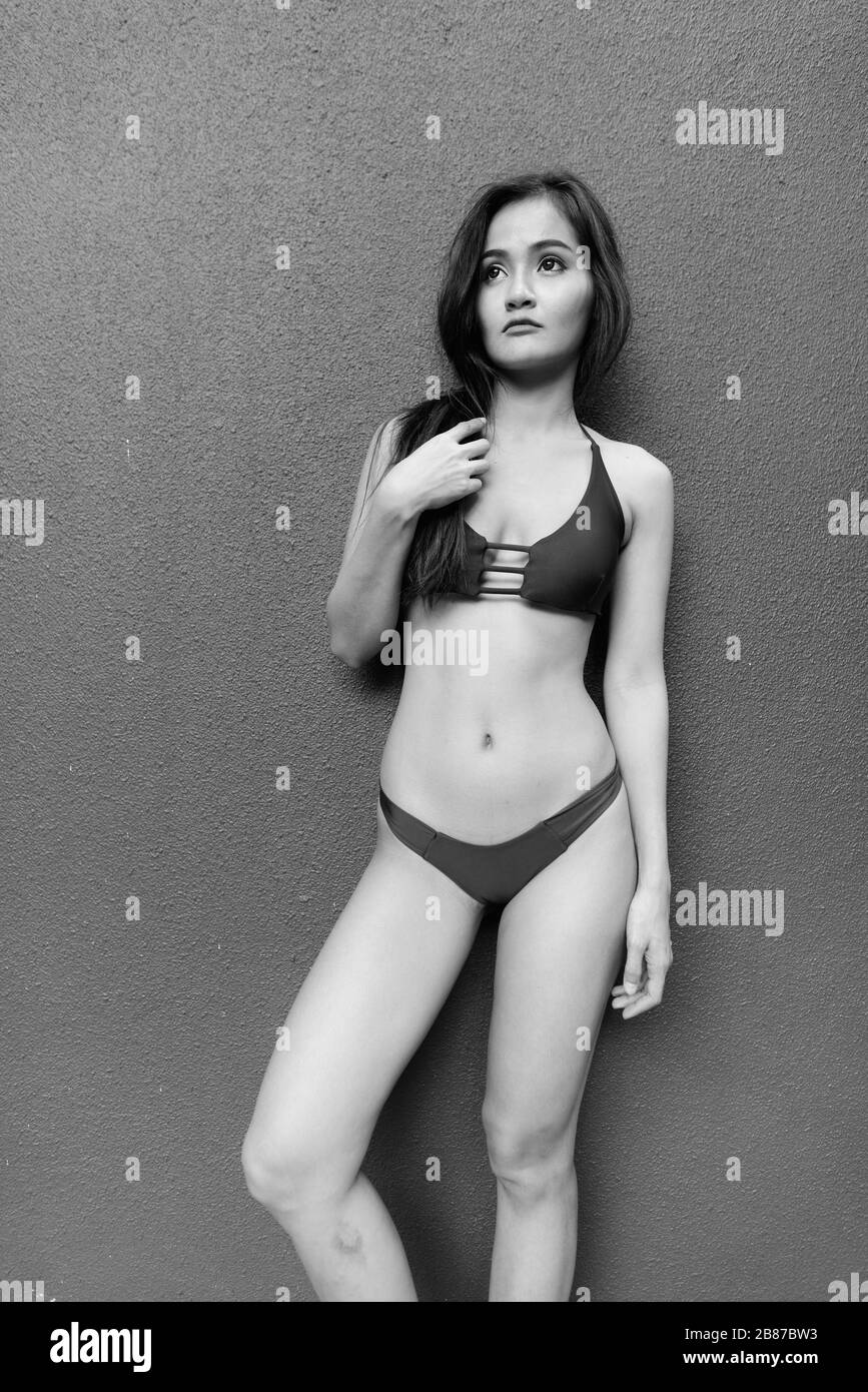 Junge schöne asiatische Frau stehend gegen graue Betonwand Stockfoto
