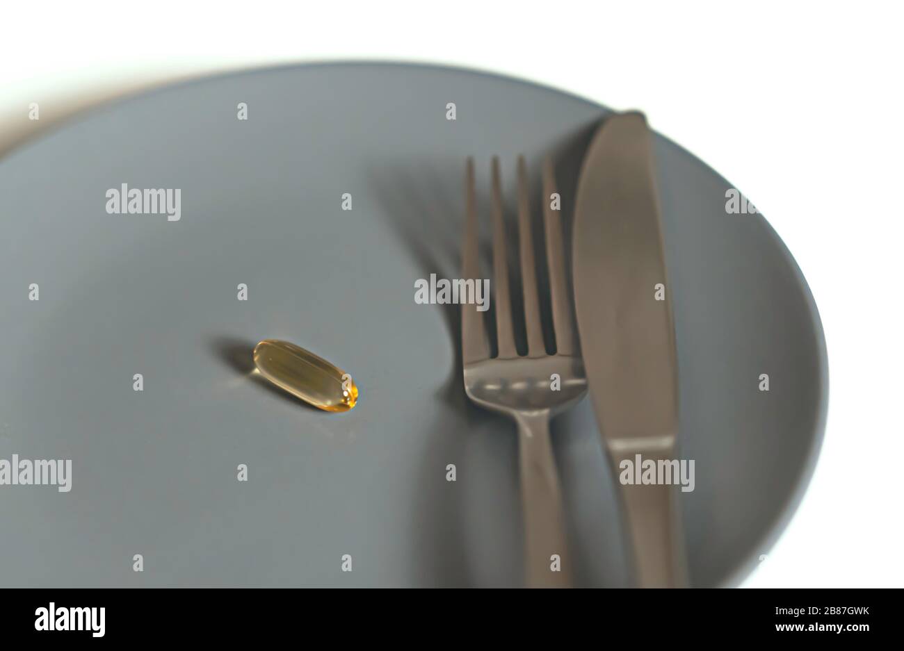 Eine blaue Platte mit einer Omega-3-Tablette, die zum Essen bereit ist. Konzept von Gesundheit und Schönheit Stockfoto