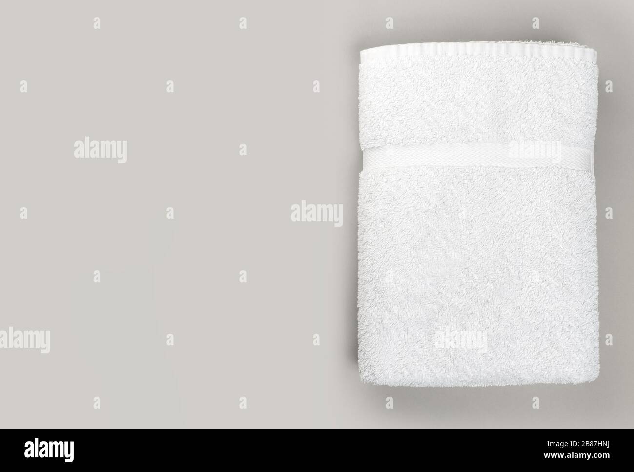 Blick auf das flauschige, weiße Badezimmertuch auf grauem Hintergrund mit Platz für Kopien Stockfoto