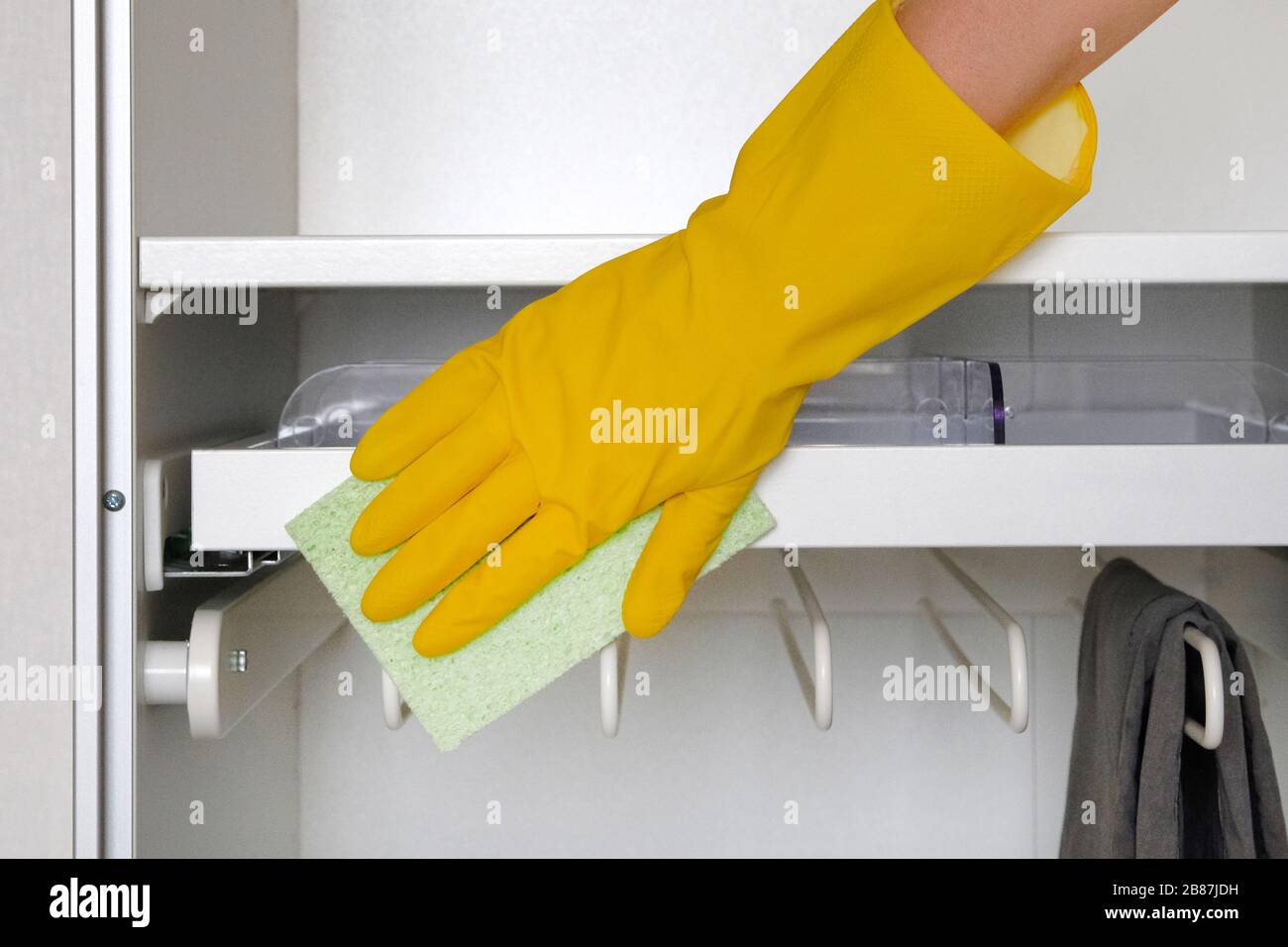 Hand in Gummi Schutzhandschuh mit Mikrofaser-Lappen reinigt einen Schrank im Raum. Hausaufgaben. Сleaning oder regelmäßige Reinigung. Stockfoto
