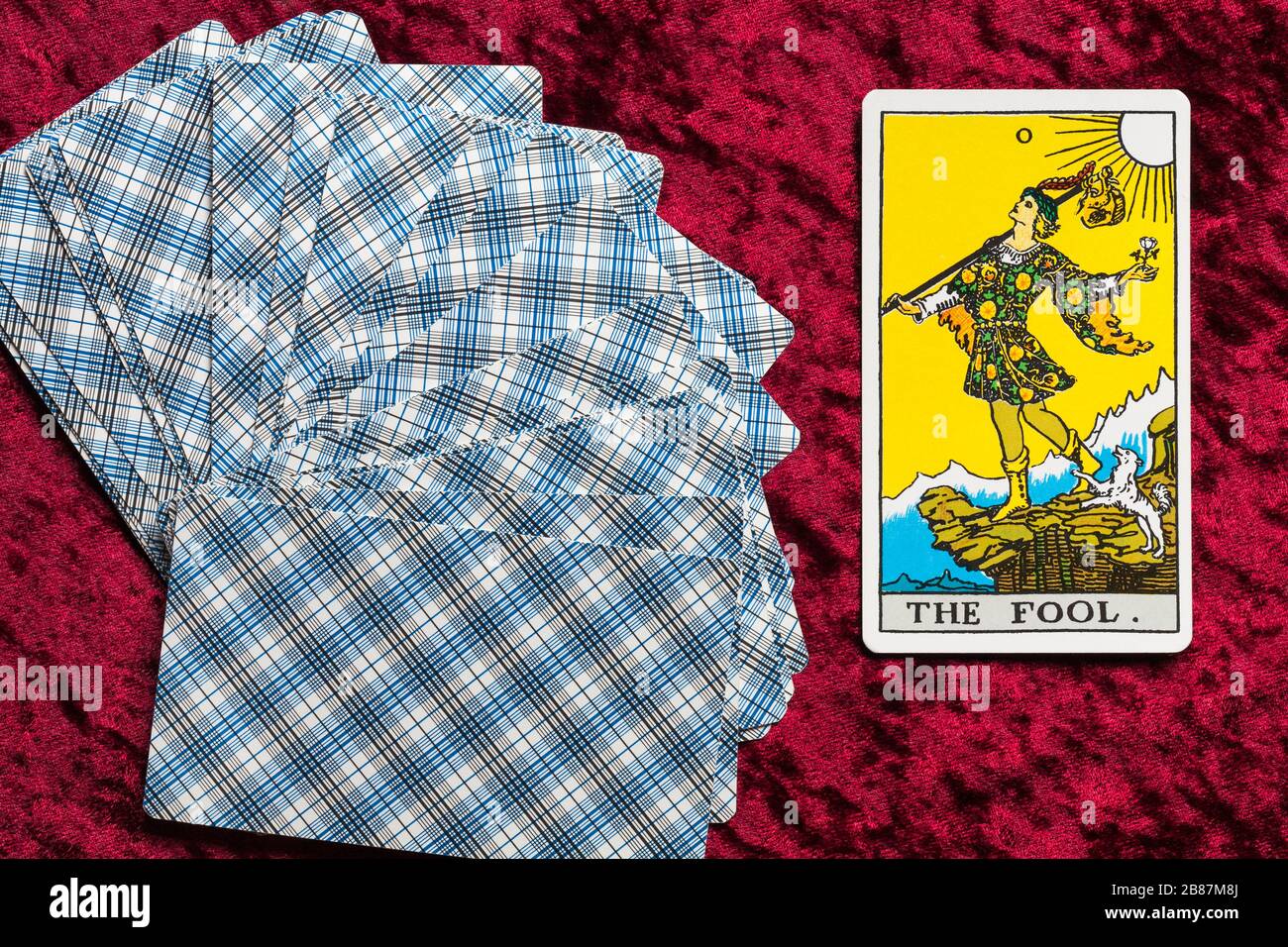Die von Pamela Colman Smith unter der Aufsicht von Arthur Edward Waite entworfenen Karten des Fahrers Tarot wurden auf rotem Tuch mit aufgehobenem Tarot-Karte aufgefächert Stockfoto