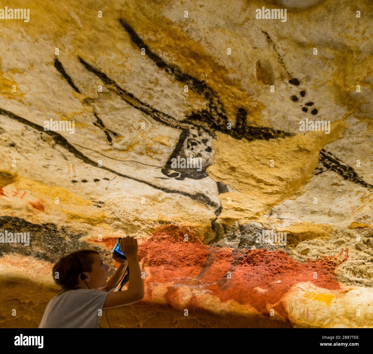 Ein junger Besucher blickt auf eine Nachbildung eines prähistorischen Höhlenmales im Lascaux Centre in Montignac, Frankreich. Der Nachbau ist von einem Stier in der Bulls' Chamber. Stockfoto