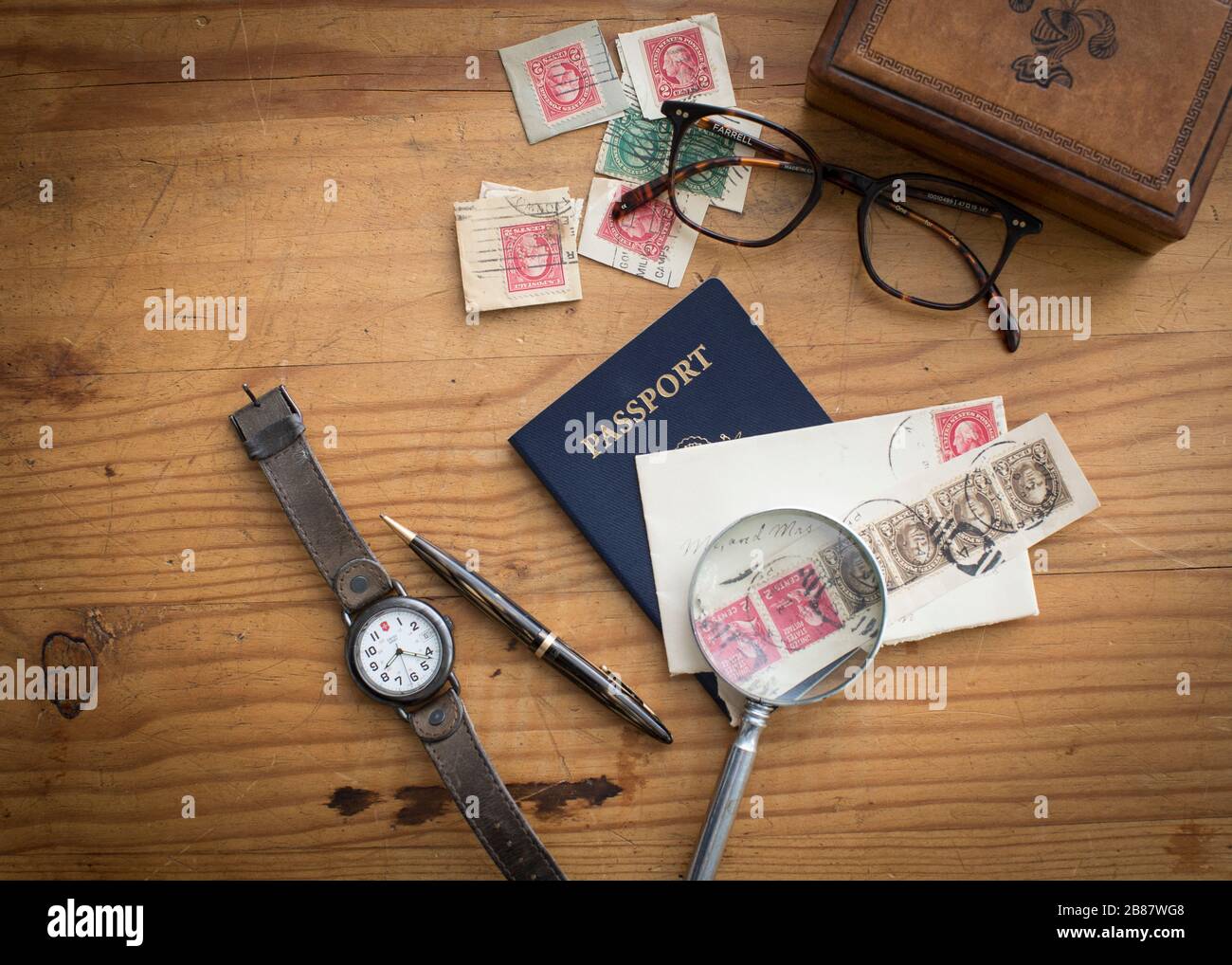 Robustes und maskulines Kiefernholz mit Lederbox, Reisepass, Uhr und Briefmarken mit anderen Herrenzubehör für einen Vatertags-Urlaubslook Stockfoto