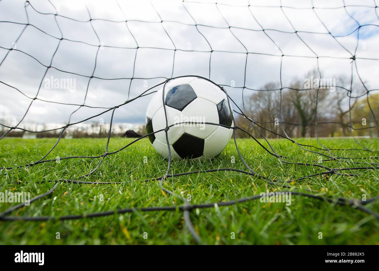 Nahaufnahme eines Fußballballs hinter dem Tornetz, Torkonzept. Outdoor-Fußballspiel, Üben von Frühjahrssport. Gesunde Aktivität und Spiele, g Stockfoto