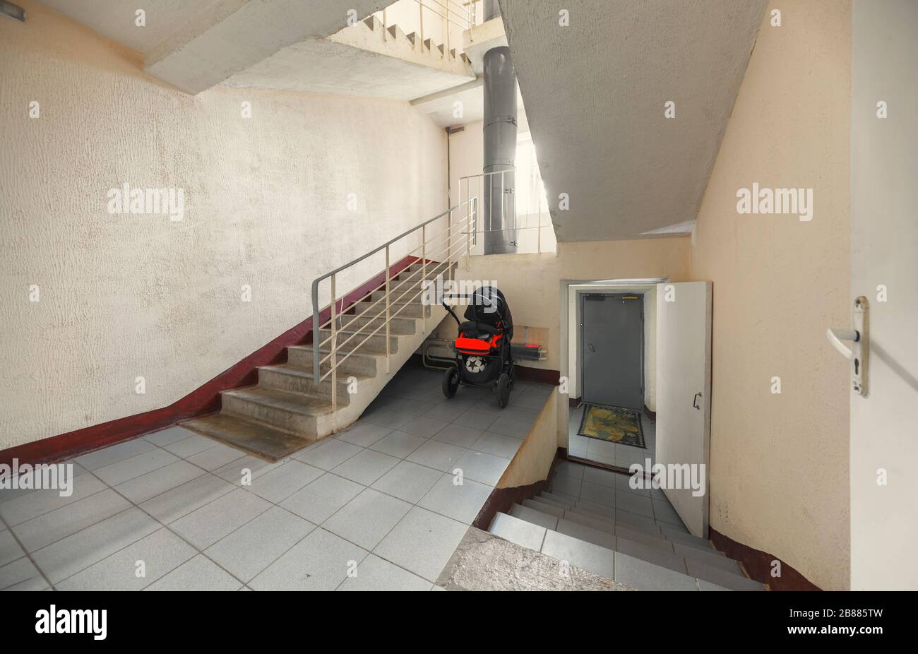 Eingang zum Treppenhaus eines Apartmentgebäudes. Babywagen in der Nähe der Treppe Stockfoto