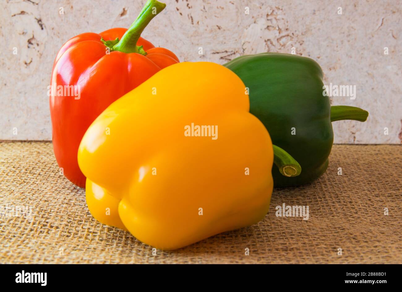 Drei süße Paprika auf dem natürlichen Hintergrund. Roter, gelber, grüner frischer Pfeffer. Gesunde, vegane und diätische Lebensmittel. Stockfoto