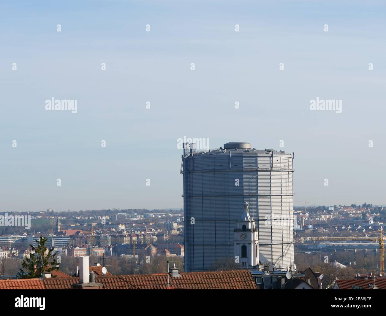 Die Kirche des Stadtteils Gaisburg in der deutschen Stadt Stuttgart vor dem Gasometer, das ein Industriedenkmal namens Gaskessel ist Stockfoto