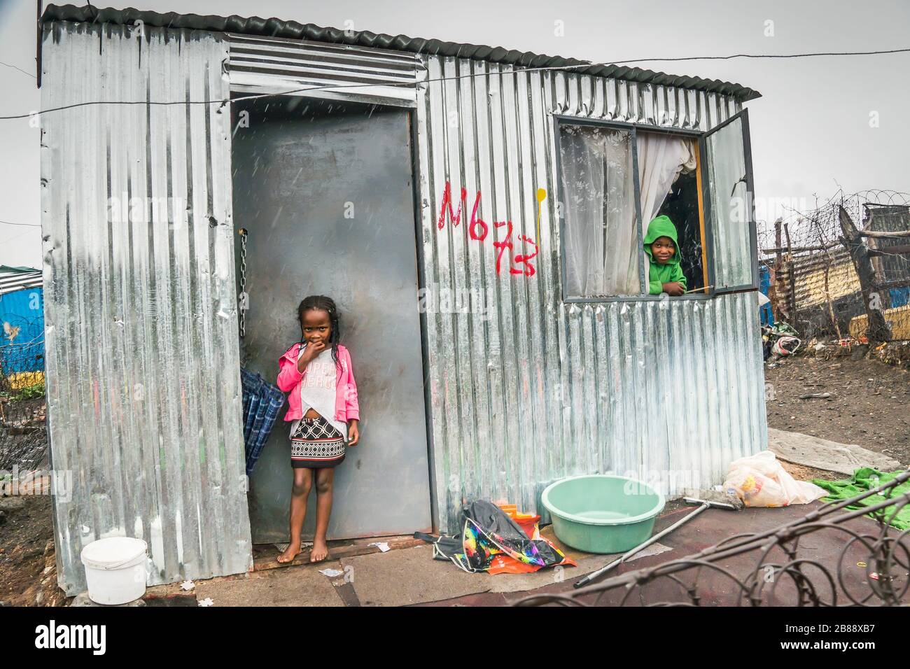 Johannesburg, Südafrika - 5. Dezember 2019 - Soweto Shanty-Stadt; Kinder leben in Blechscheren; regnerischer Tag. Stockfoto