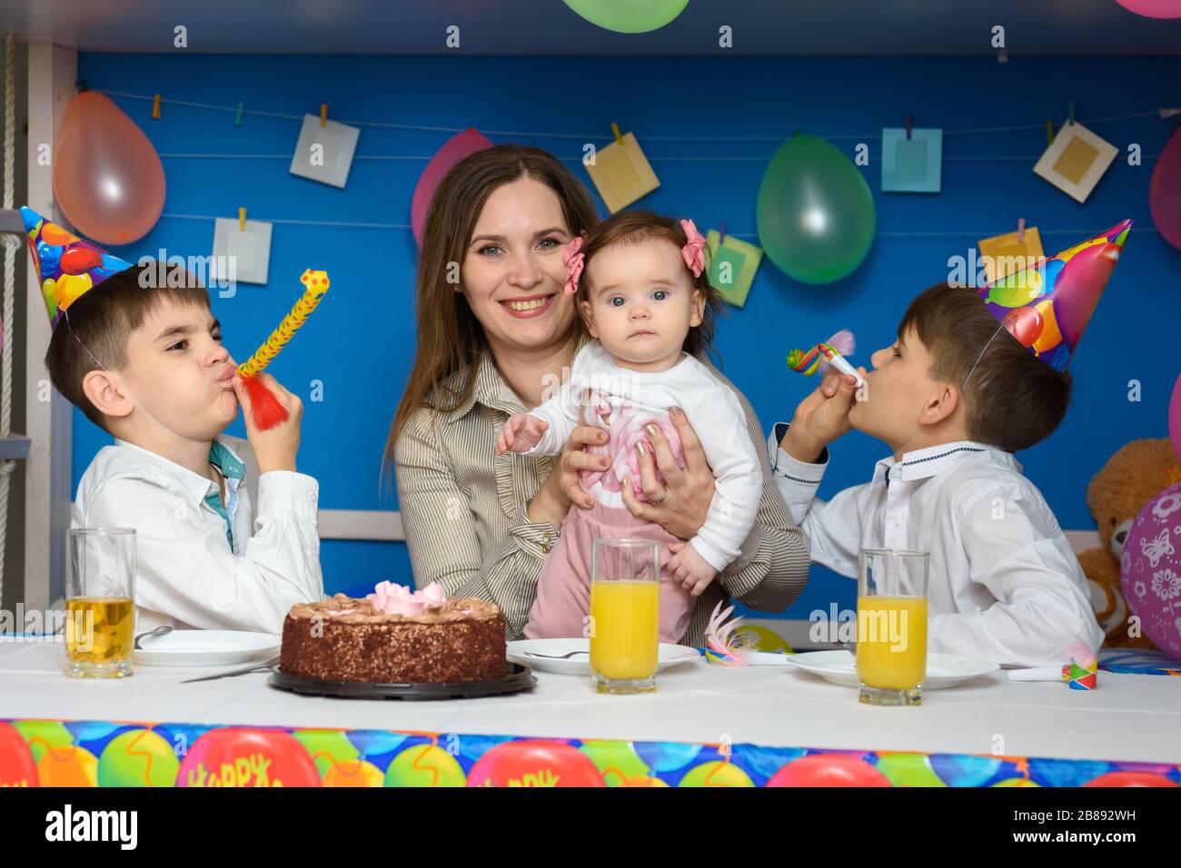Kinder blasen bei einer Geburtstagsfeier freudig in die Glocken Stockfoto