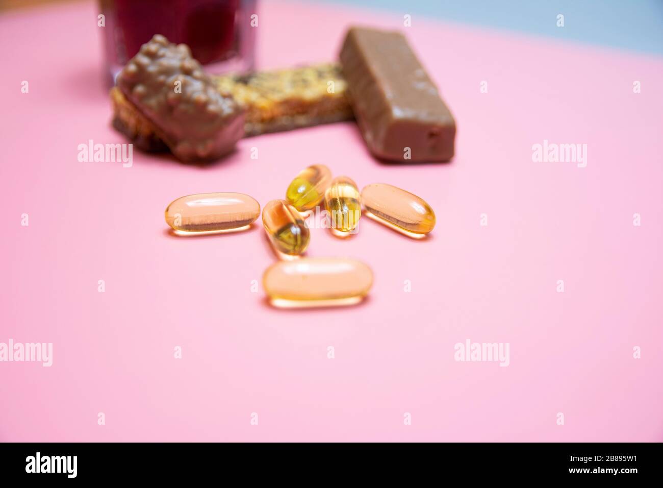 Schokoladenprotein-Bar mit gesunder Omega-3-Mahlzeit auf pinkfarbenem Hintergrund. Stockfoto