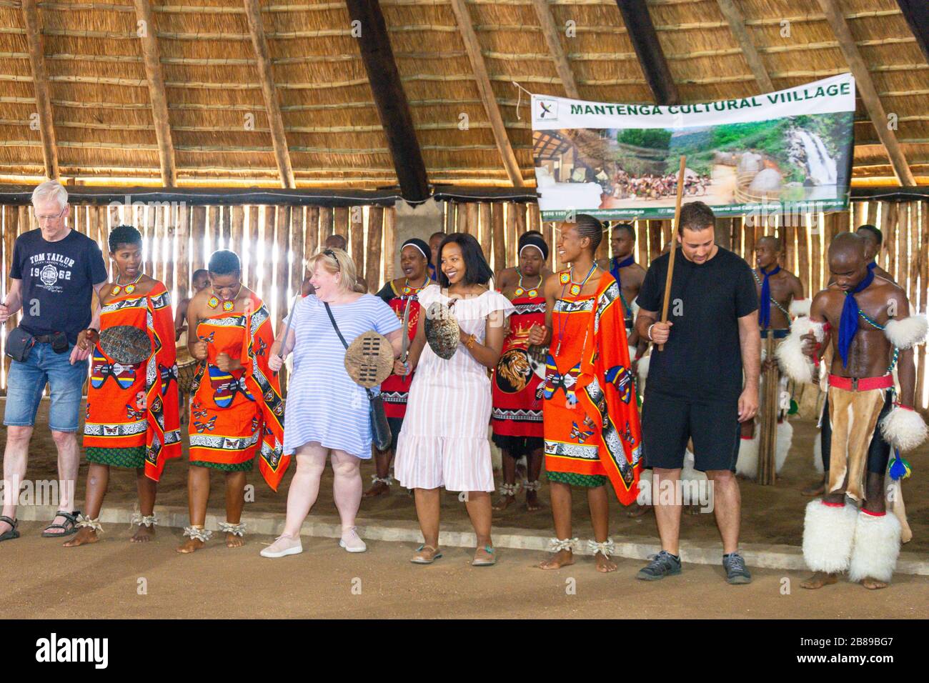 Kulturelle Tänzerinnen und Touristen im Swazi Cultural Centre, Mantenga Nature Reserve, Lobamba, Ezulwini Valley, Königreich Eswatini (Swasiland) Stockfoto