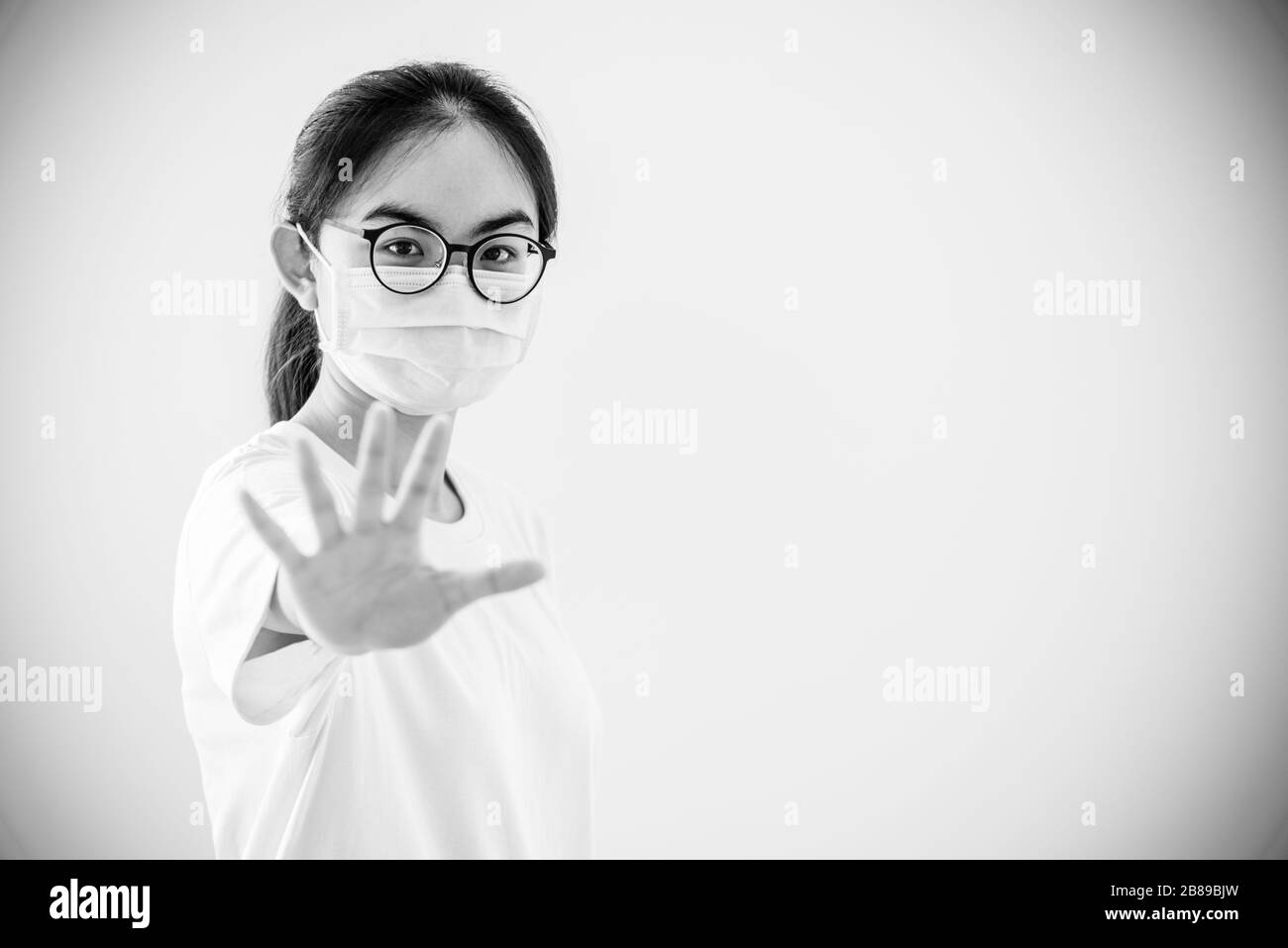 Schwarz-Weiß-Porträt Asian junge Frau trägt Brille und Maske zum Schutz vor Coronavirus, Mädchen zeigen Handstopp-Coronavirus-Ausbruch, Kopie Stockfoto