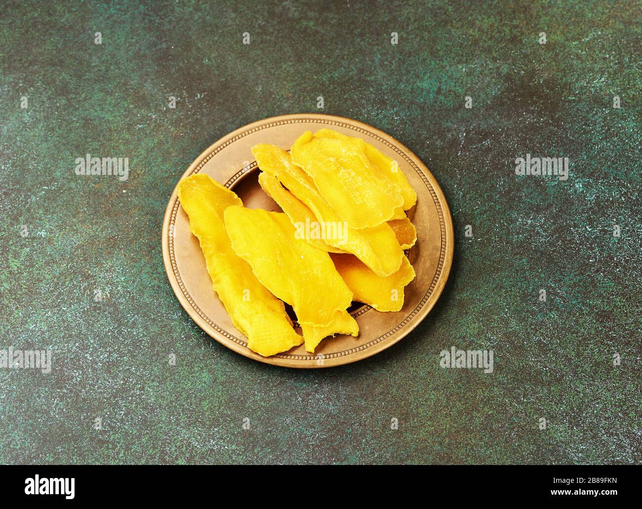 Getrocknete Mango-Früchte auf grünem Grund. Mango in gelber Scheiben. Draufsicht. Stockfoto