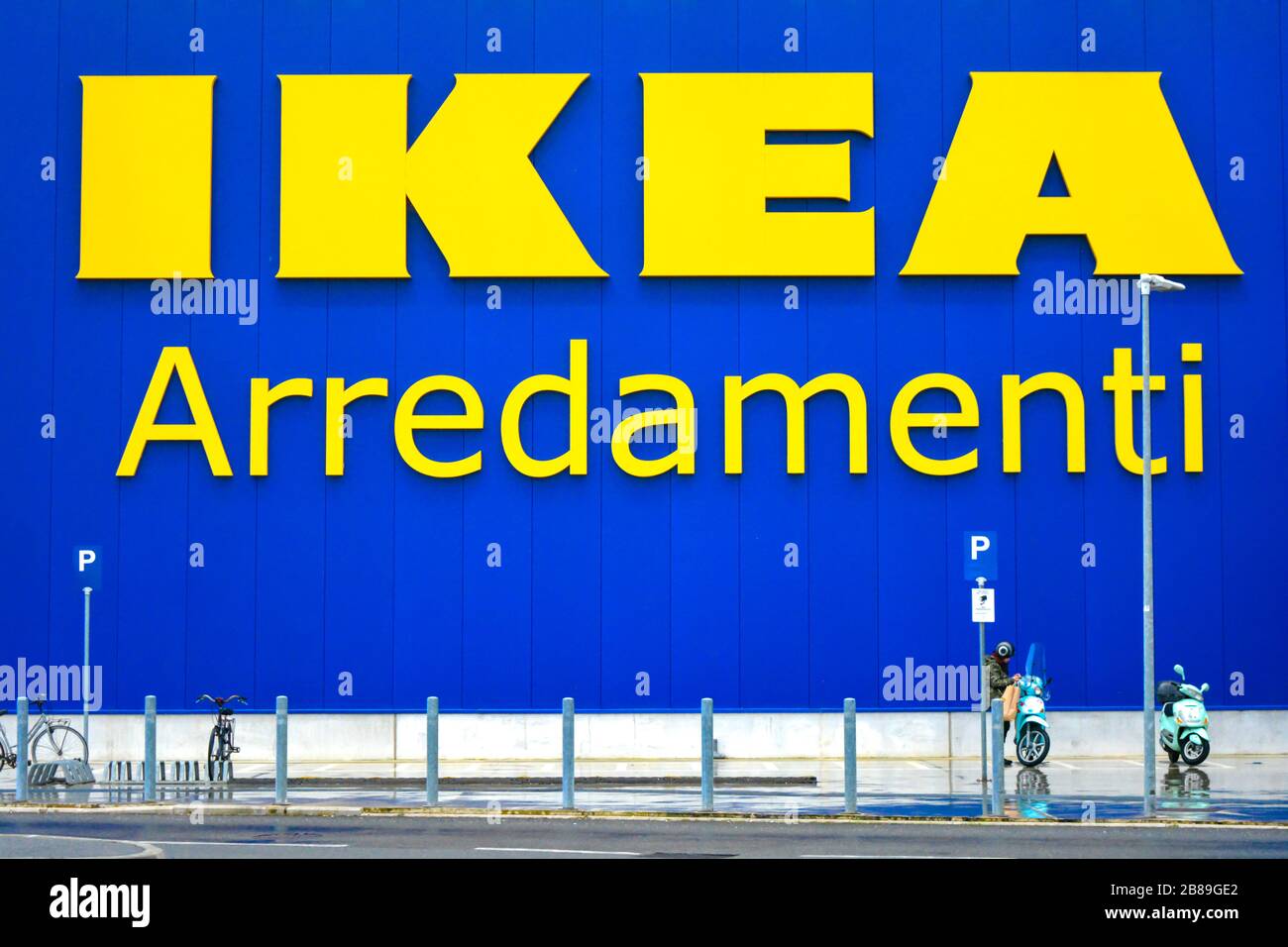 Nahaufnahme eines Ikea-Zeichens. Berühmte schwedische Möbelhauskette. Eine Frau einige Motorräder und Fahrräder vor dem Hotel geparkt. Schild bedeutet "Möbel" Stockfoto