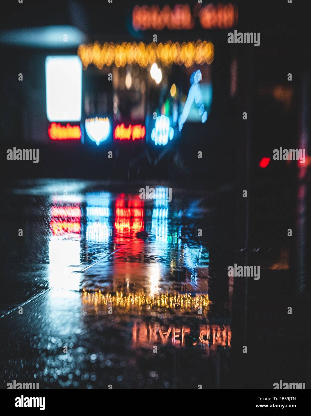 Neonschilder spiegeln sich in einer Pfütze Stockfoto