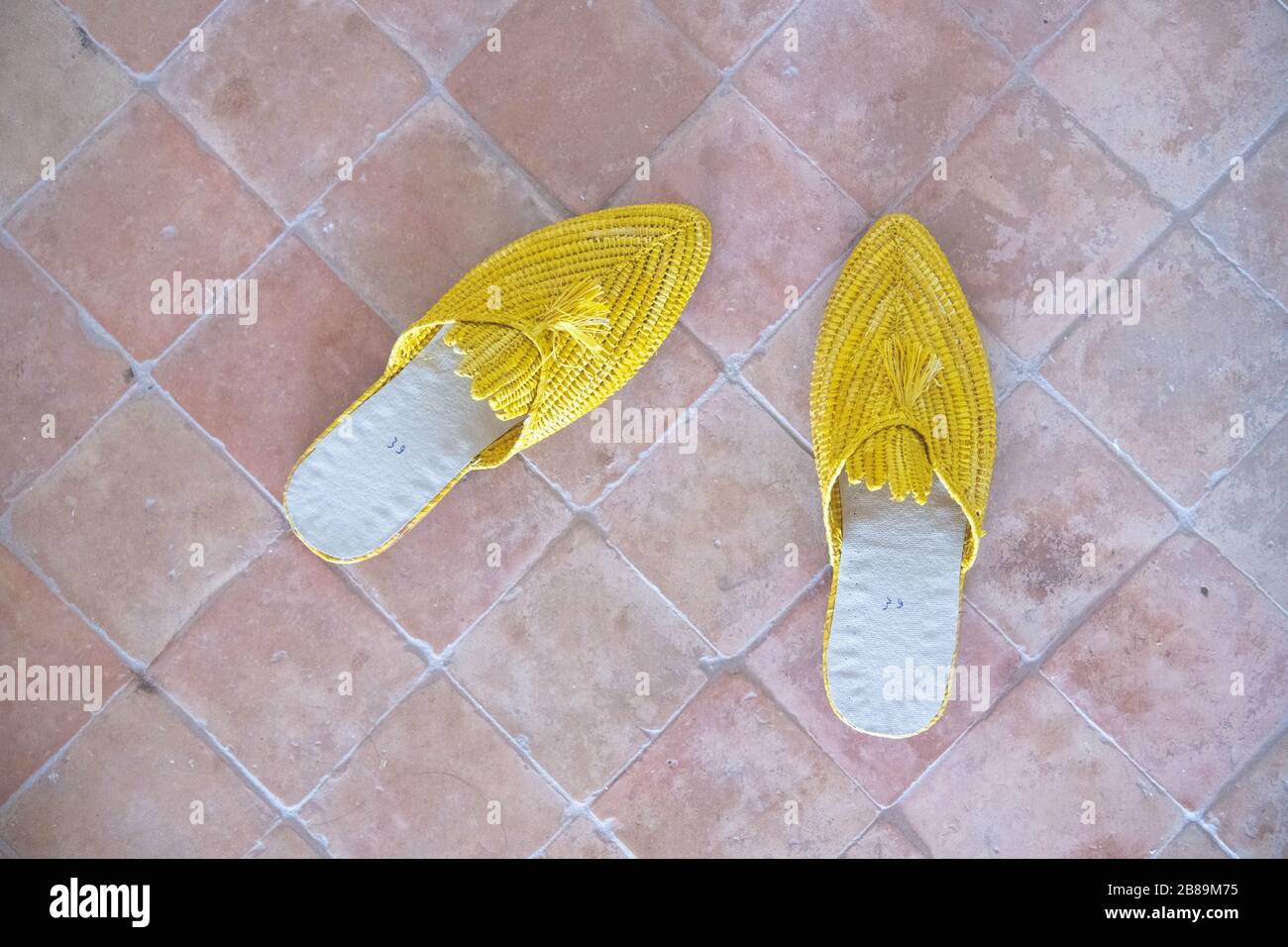 Gelbe Pantoffeln auf einem Ziegelboden Stockfoto