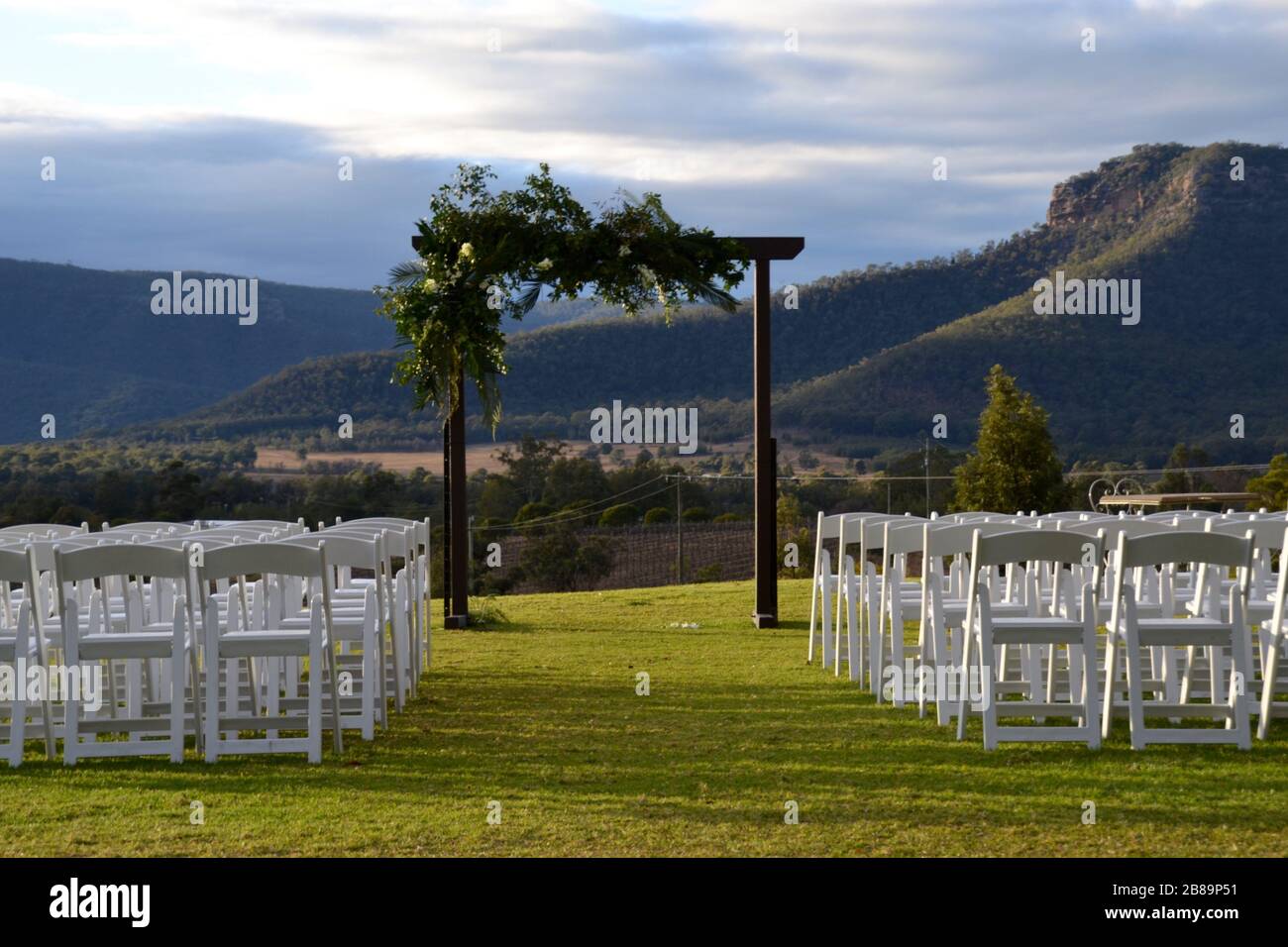 Hochzeitsbogen mit Reihen weißer Stühle bereit für eine Zeremonie mit Blick auf das Hunter Valley in NSW, Australien Stockfoto