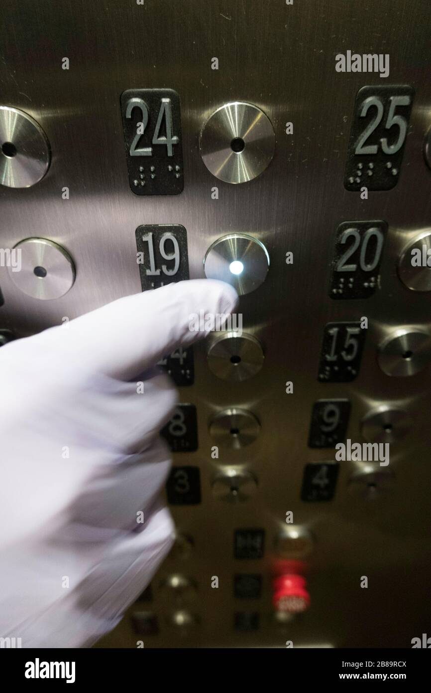 Mit Handschuhen drücken der Elevator-Taste während des COVID-19-Ausbruchs, NYC, USA Stockfoto