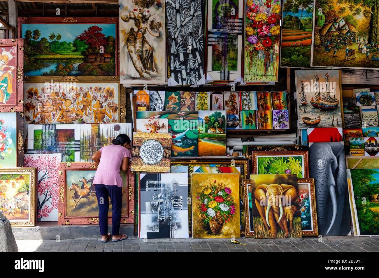 Eine Frau betrachtet die Art for Sale auf dem Sukawati Art Market, Gianyar, Bali, Indonesien. Stockfoto