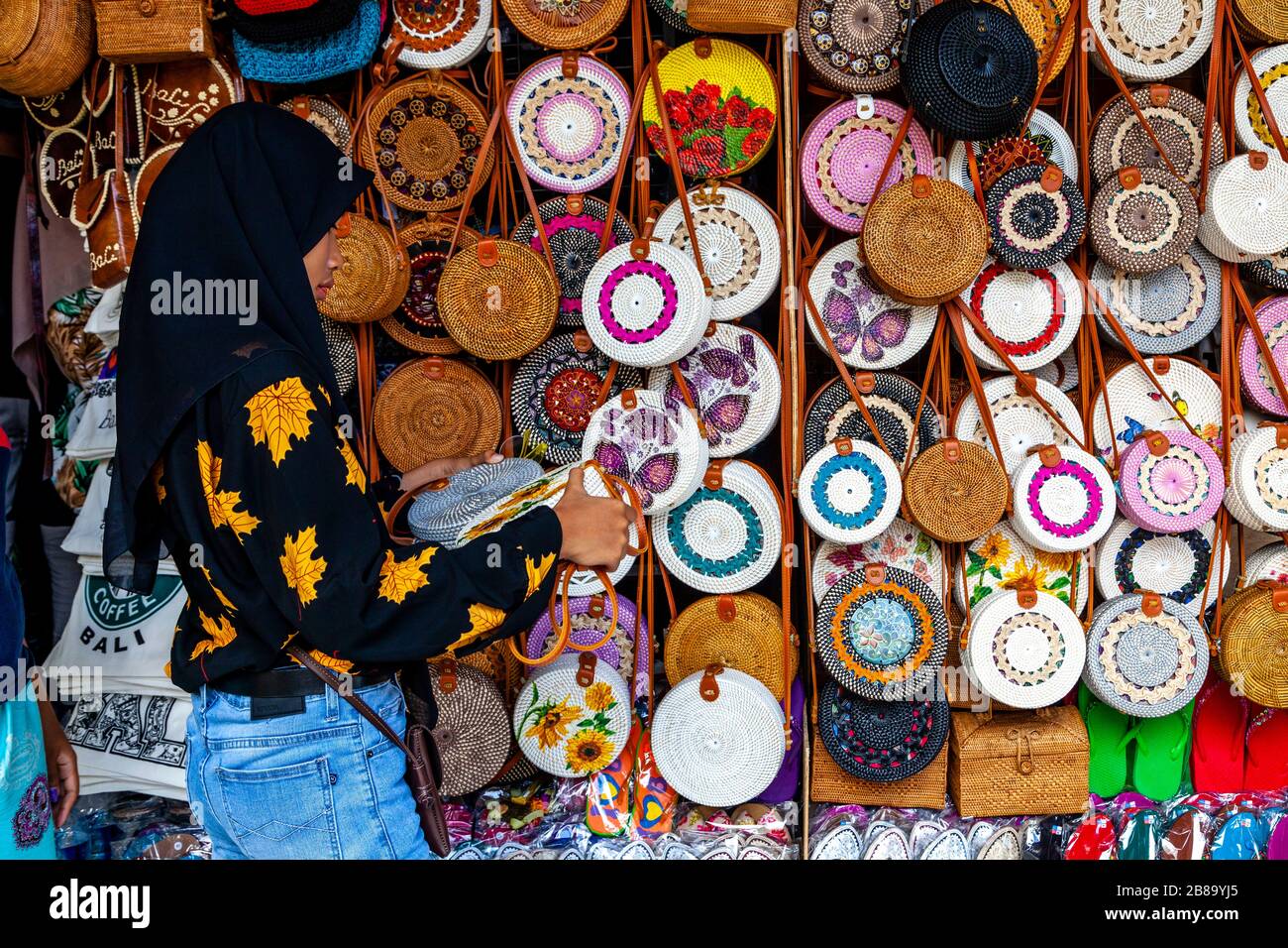 Eine junge Frau durchstöbert die Taschen/Handtaschen, die zum Verkauf stehen, den Sukawati Art Market, Gianyar, Bali, Indonesien. Stockfoto