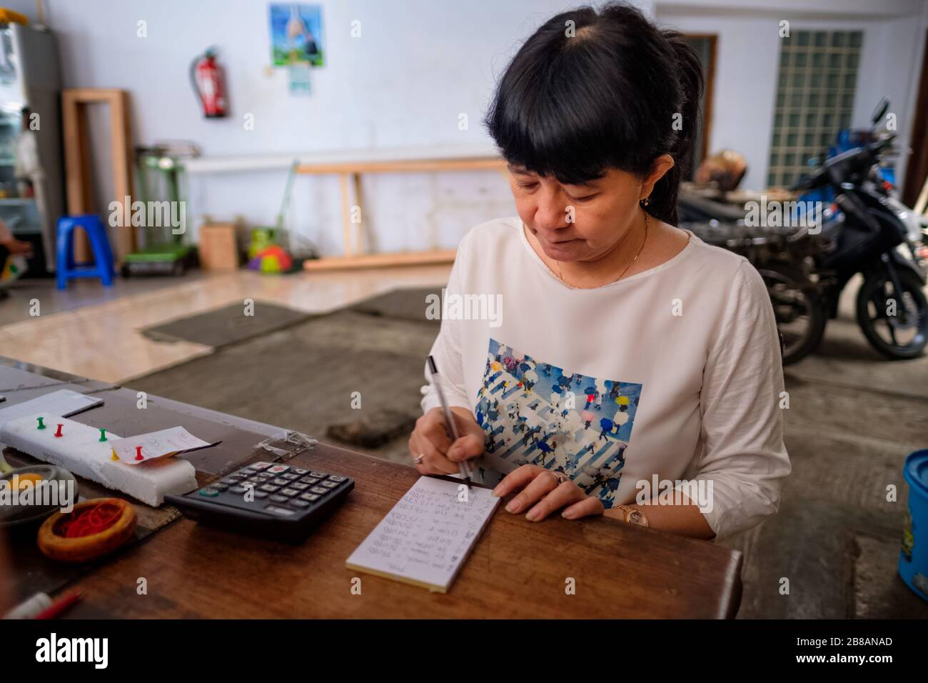 Indonesische Frauen in Asien, die Eigentümerin eines kleinen, örtlichen Familienunternehmens oder lokal Warung genannt werden, berechnen den Gewinn an ihrem Schreibtisch. Selektives Focu Stockfoto