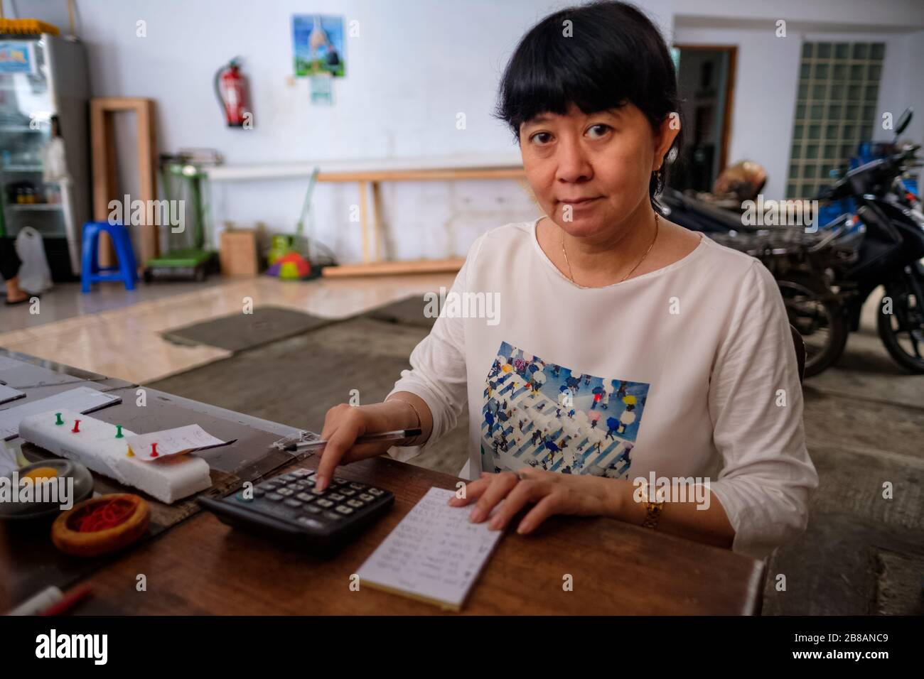 Indonesische Frauen in Asien, die Eigentümerin eines kleinen, örtlichen Familienunternehmens oder lokal Warung genannt werden, berechnen den Gewinn an ihrem Schreibtisch. Selektives Focu Stockfoto