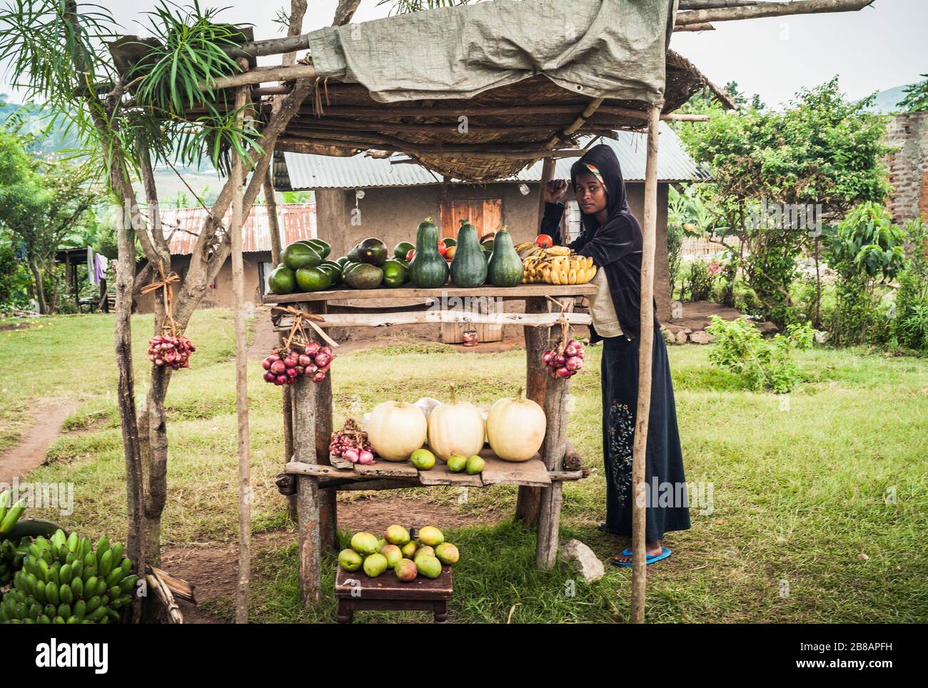 Kasese, Uganda - 22. Juli 2011: Junge schwarze Frau vor Ort, die Obst auf einem Markt Stall oder Stand verkauft. Stockfoto
