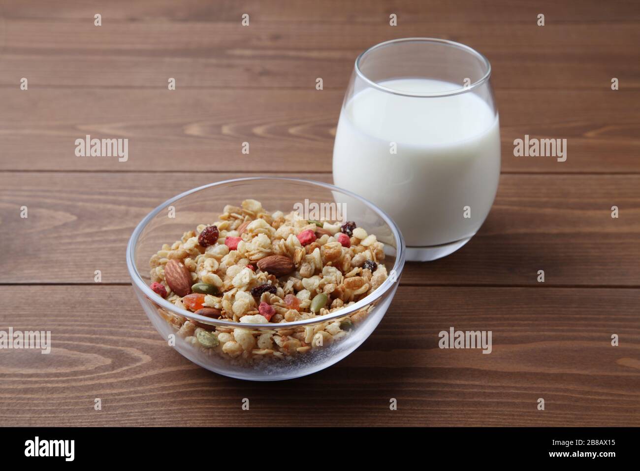 Müsli in der Schüssel mit Milch isoliert auf Holztisch Stockfoto