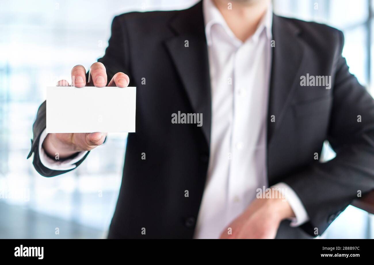 Legerer Business man hält leere weiße Visitenkarte im modernen Bürogebäude. Freier leerer Kopierspeicher. Stockfoto