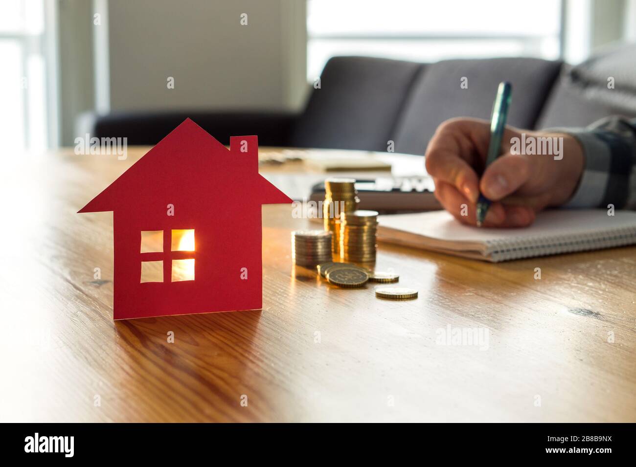 Mann zählt Hauspreis, Hausversicherungskosten, Sachwert oder Miete auf Papier. Realtor oder Immobilienmakler schreiben Angebot. Stockfoto