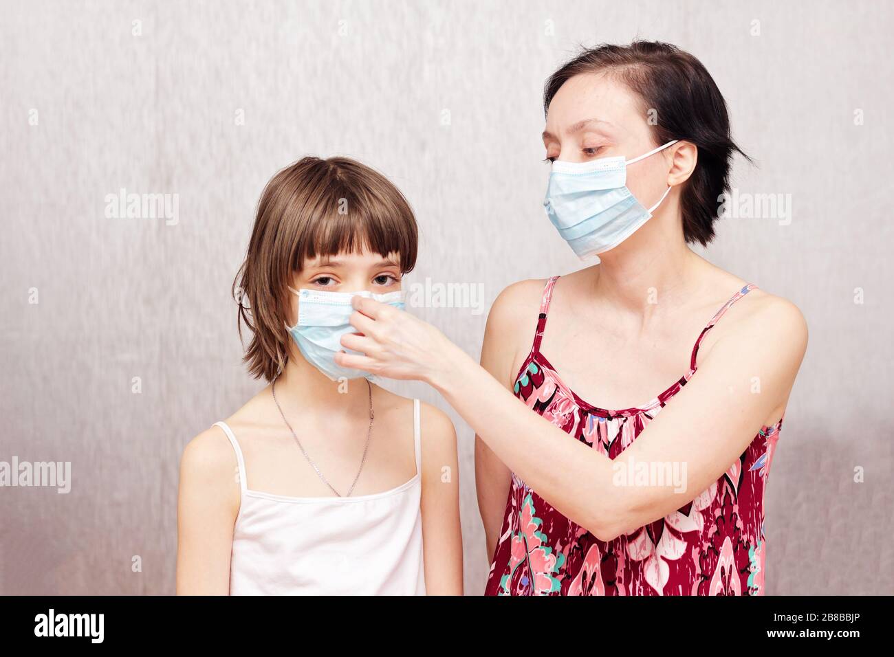Mutter und Tochter mit medizinischen Schutzmasken auf den Gesichtern. Stockfoto