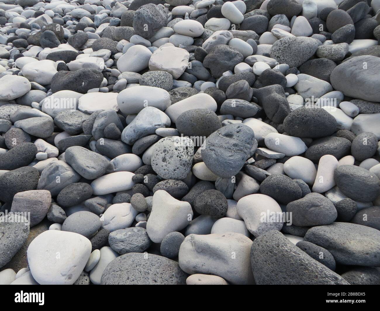 Mischung aus weißen und grauen / grauen Steinen auf dem Boden oder am Strand von Island, reine Natur, strukturierter Hintergrund mit Struktur mit hellen und dunklen Farben Stockfoto