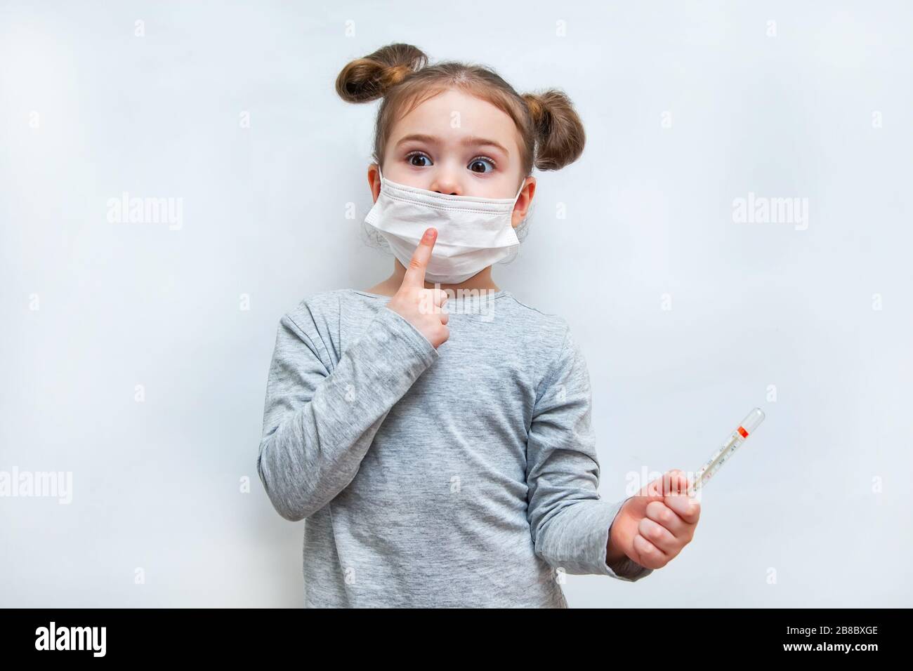 Kleines Mädchen in einer Einwegmaske den Finger hoch. Epidemischer Schutz durch Coronavirus Stockfoto