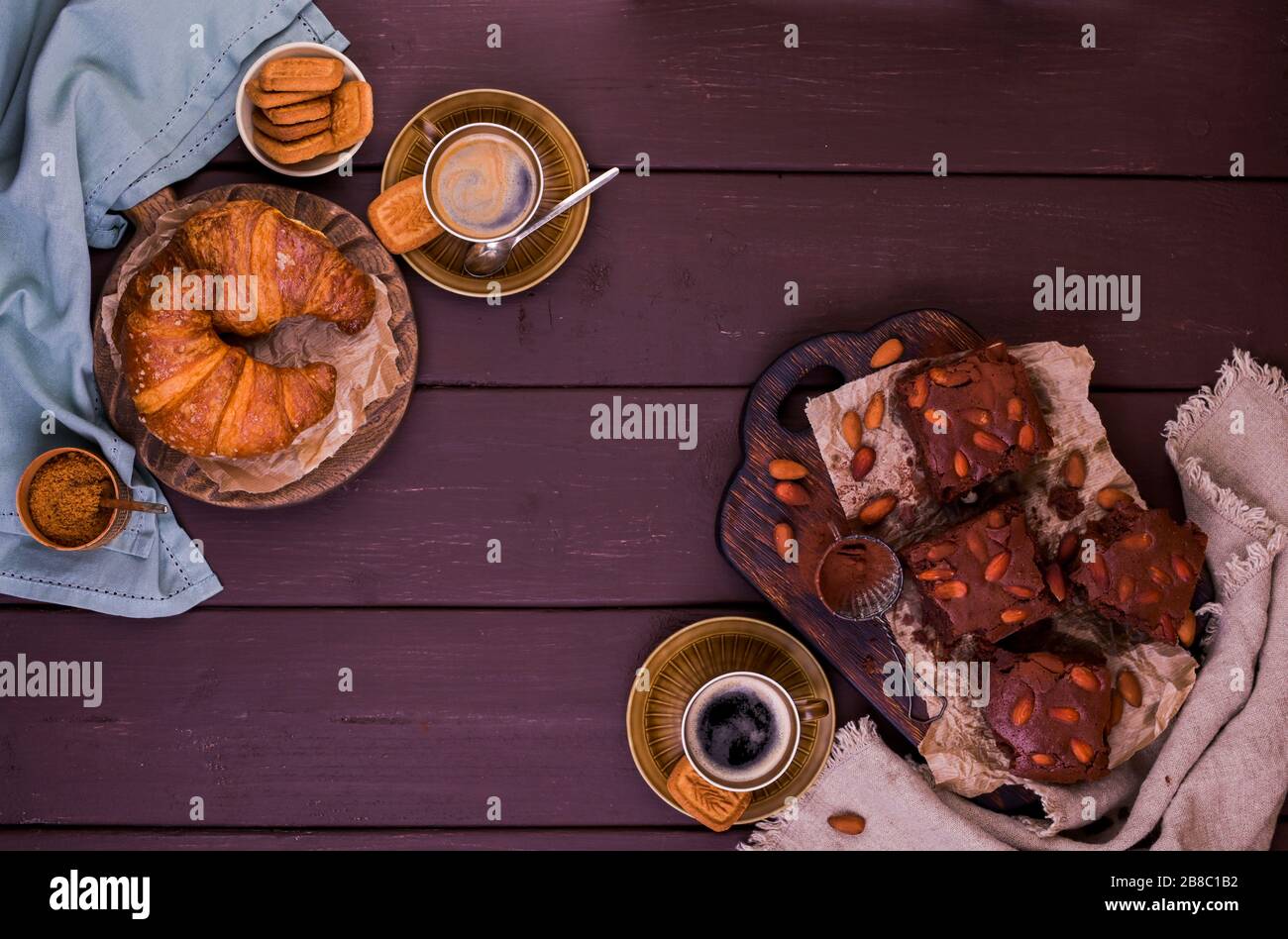 Brownie, Chocolate Cakes mit Mandeln auf einem Holzbrett und Croissant, mit Kakao bestreut. Serviert werden hausgemachte Kuchen. Draufsicht. Freier Speicherplatz für Text. Stockfoto