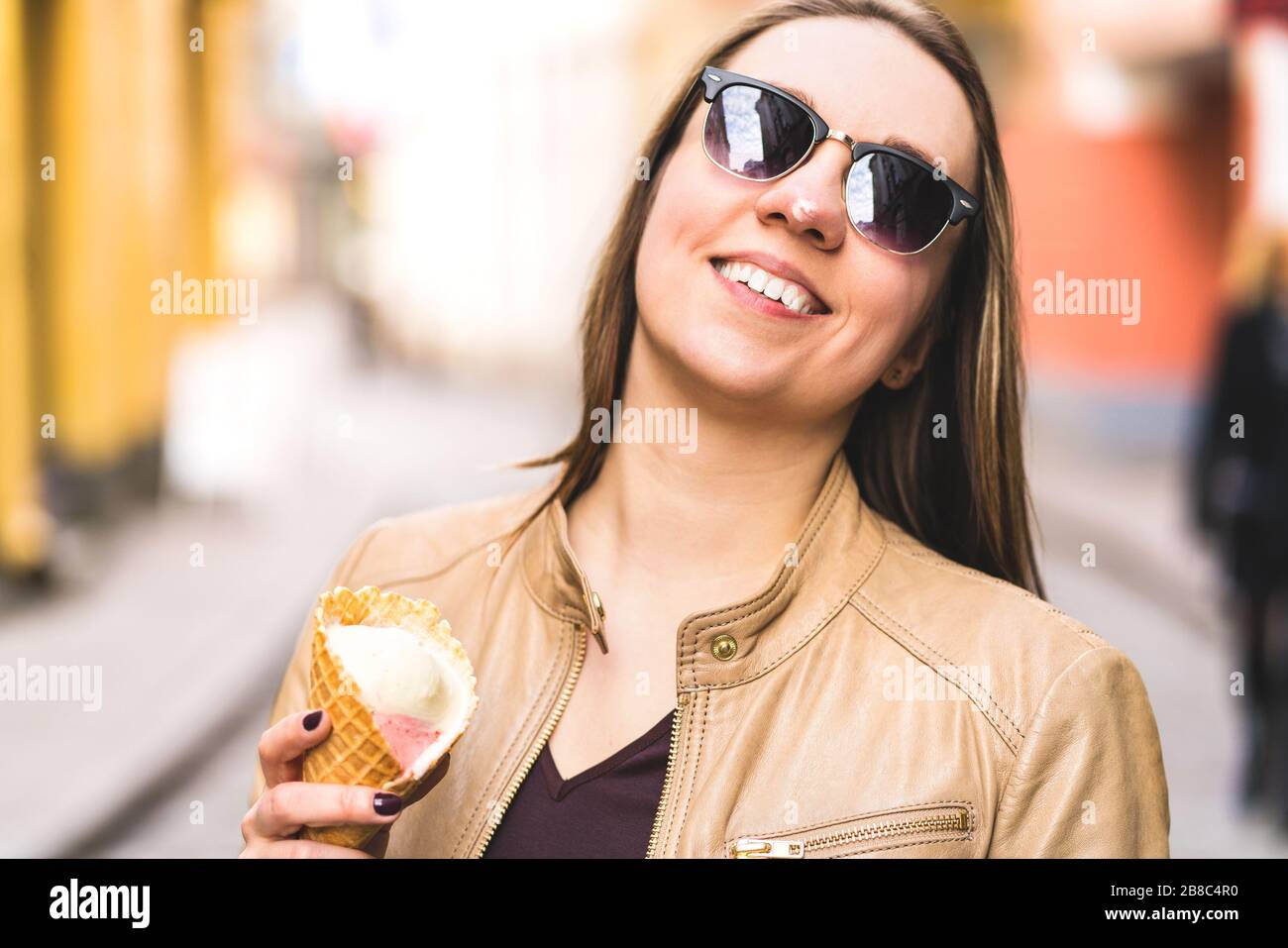 Frau mit geschmolzenem Eis an der Nase. Fröhliche lächelnde Person, die schmelzende Eiscreme in der Stadt isst. Unordentliches Gesicht. Stockfoto