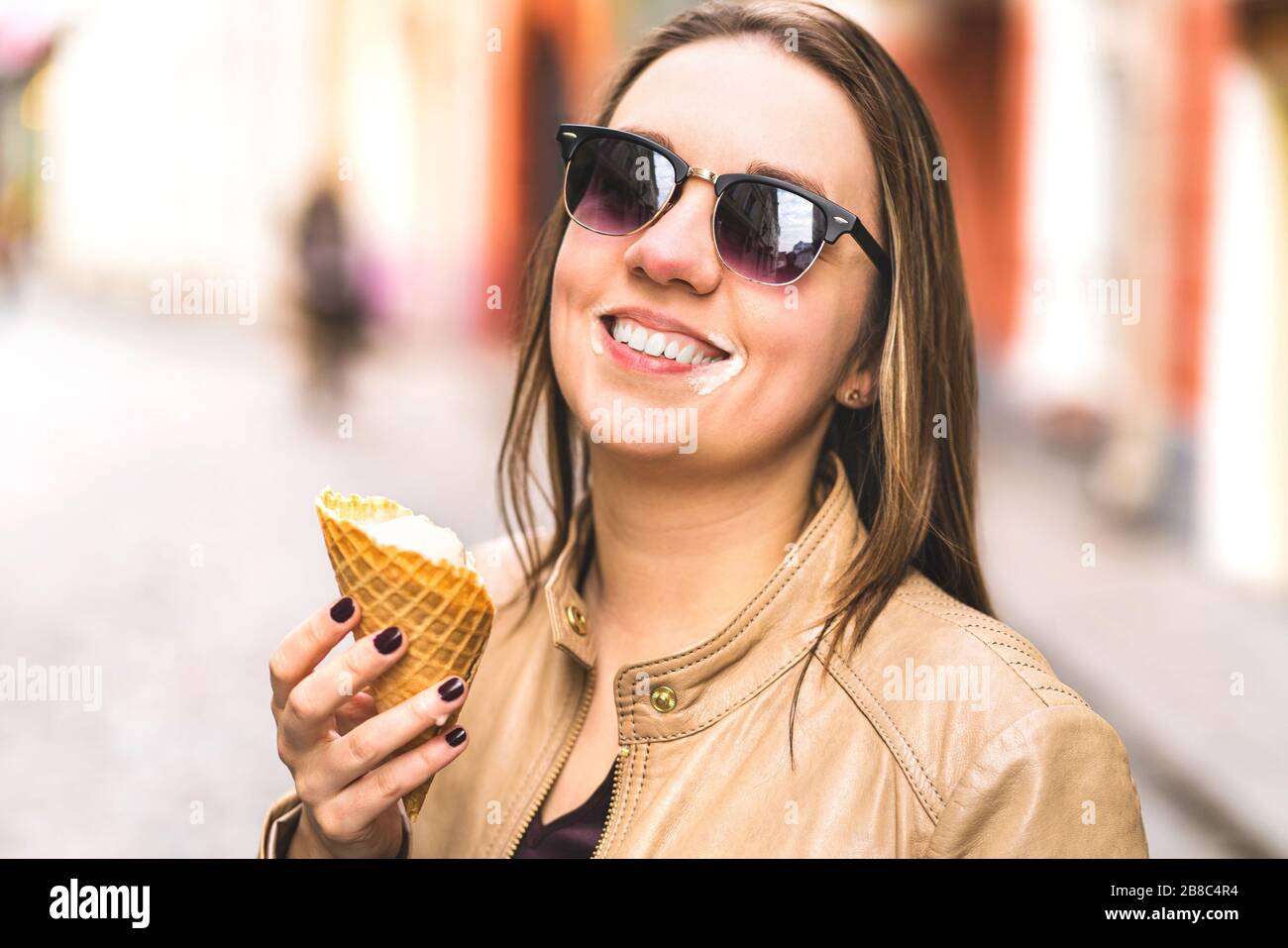 Eiscreme auf unordügem Gesicht. Fröhliche lachende Frau, die in der Stadt Schmelzen und Eis tropft. Stockfoto