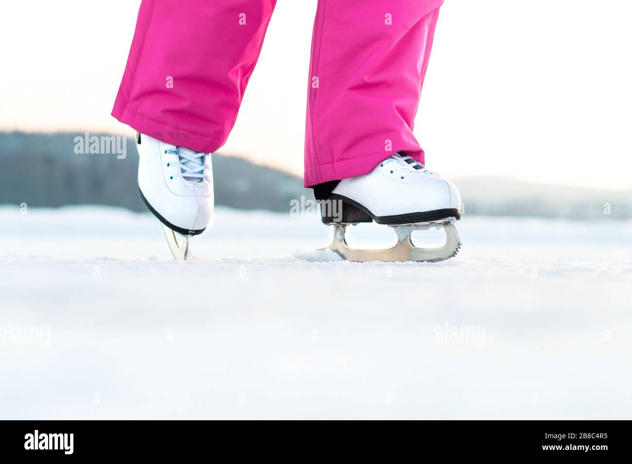 Mädchen Schlittschuhlaufen auf Eis im Freien. Skater auf gefrorenem See oder Teich. Junge Frau kickend. Eiskunstlaufübung oder -Training. Winterspaß im Winter. Stockfoto