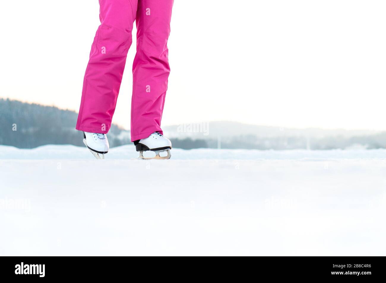 Schlittschuhlaufen für Frauen auf einer Outdoor-Strecke. Skater trainieren und trainieren im Winter. Eiskunstlauf auf einem See oder Teich. Negativer Kopierbereich. Stockfoto