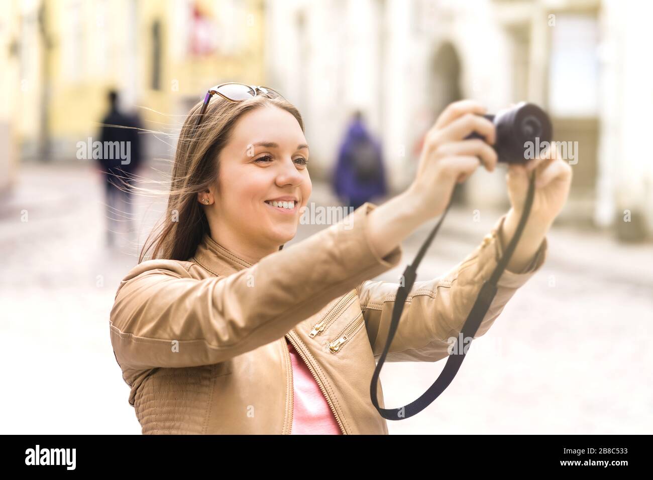 Frau fotografiert im Urlaub. Fröhliche Reisende, die Fotos mit Digitalkamera machen. Touristen in der Altstadt in Europa. Stockfoto