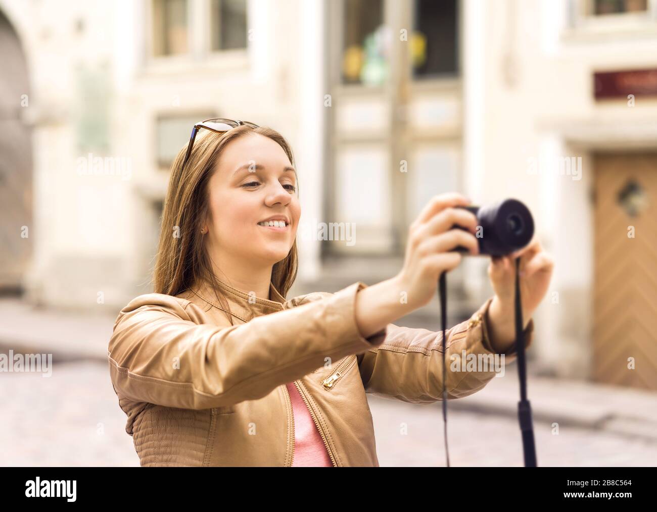 Lächelnde Frau fotografiert mit Digitalkamera auf der Straße in der Altstadt. Urlaubsbilder im Urlaub. Konzept für Reisefotografie. Stockfoto