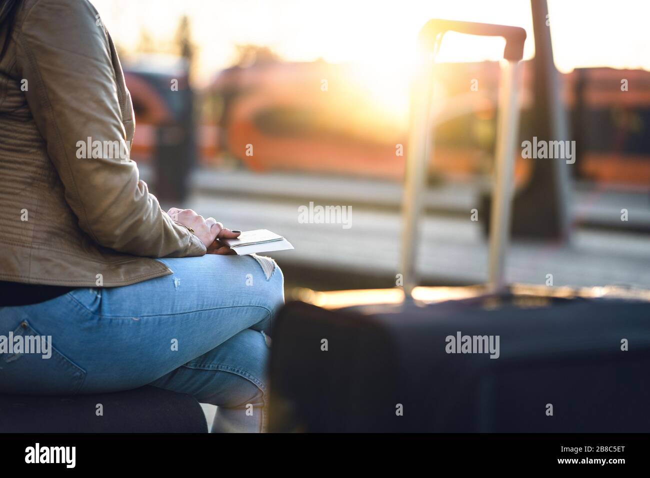 Frau wartet mit Pass, Ticket und Koffer auf Zug. Dame mit Gepäck in der Station bei Sonnenuntergang. Reise-, Urlaubs- und Verkehrskonzept. Stockfoto