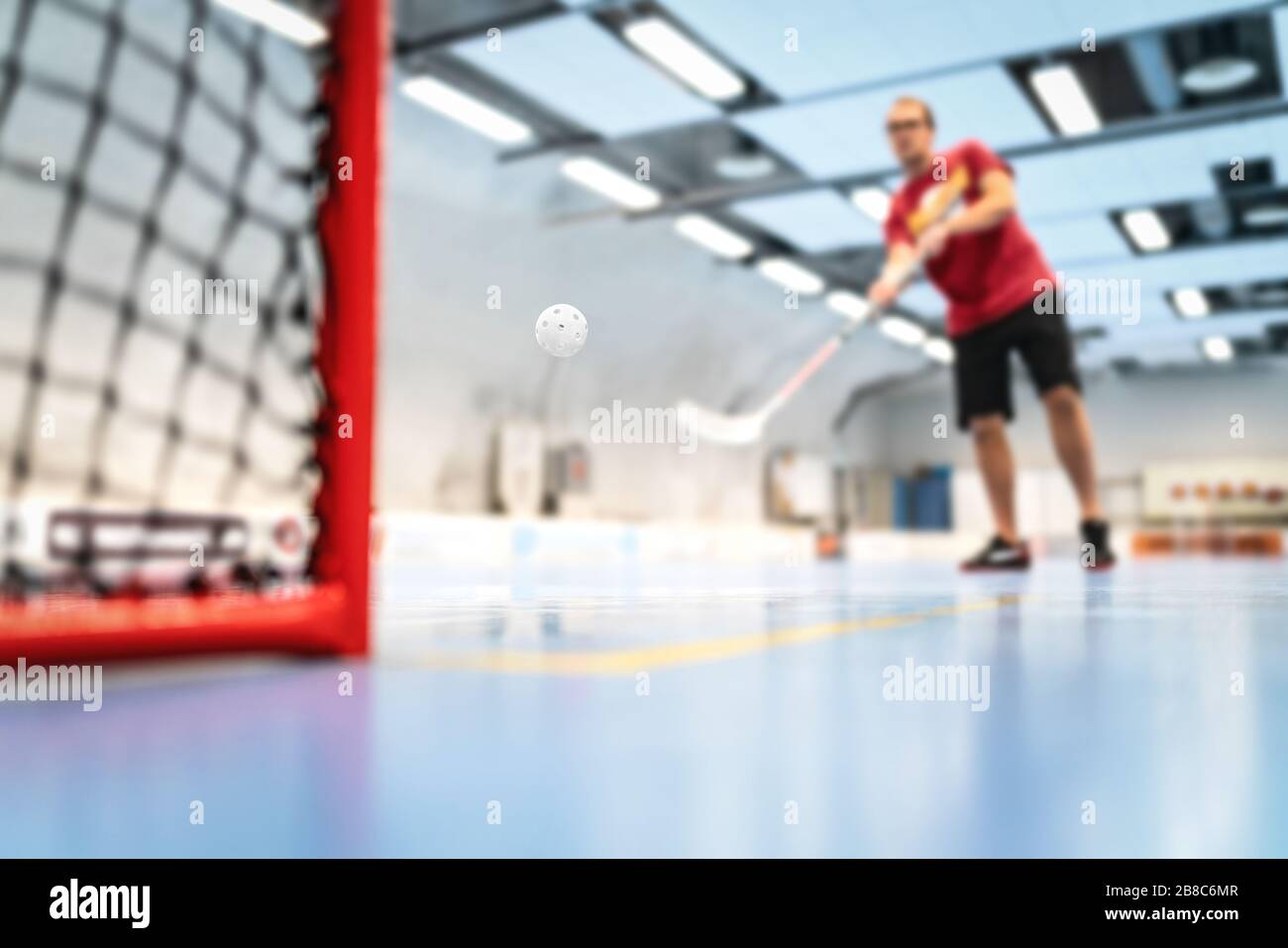Floorballtraining auf dem Platz. Mann trainiert in der Arena Hockey. Schlag auf Tor. Stockfoto
